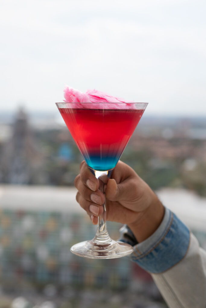 A red and blue cocktail with pink cotton candy on top