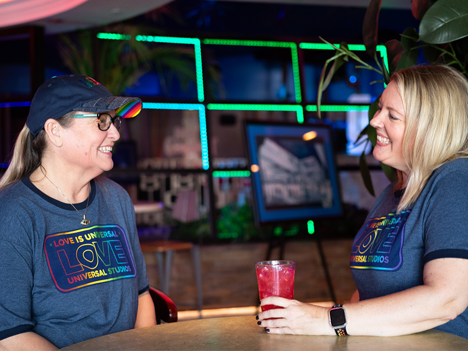 Two women smile over drinks at Red Coconut Club
