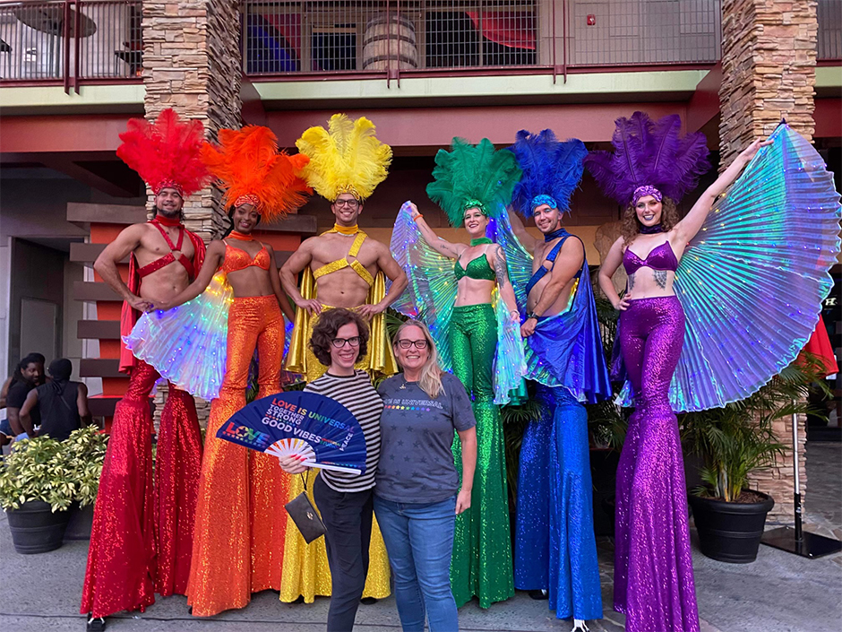 Two women pose with rainbow stilt walkers at Universal CityWalk