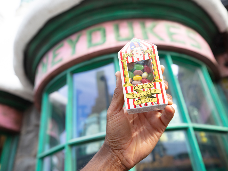 A guest holds up a box of Bertie Bott's Every Flavour Beans outside Honeydukes in The Wizarding World of Harry Potter.
