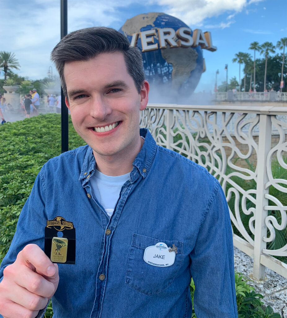 Jake standing in front of the Universal globe holding a Twister pin