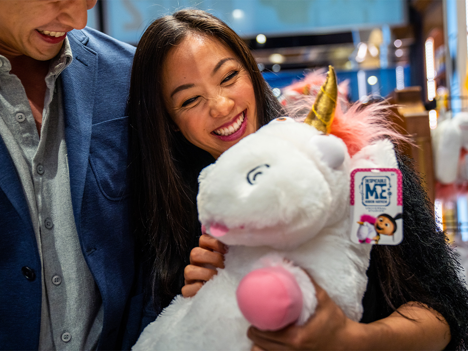 A woman holds a plush unicorn at Super Silly Stuff in Minion Land.