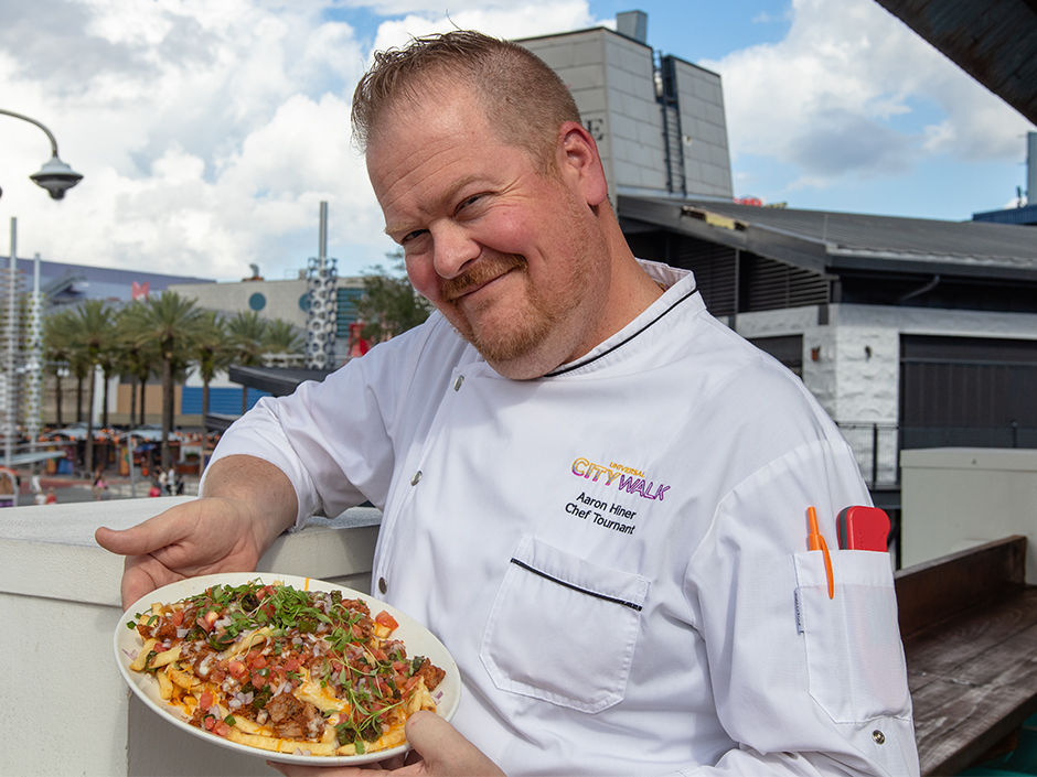 Universal CityWalk Chef Aaron Hiner posing with the Colorado Springs Loaded Green Chile Fries for Veterans and Military Families Appreciation Month.