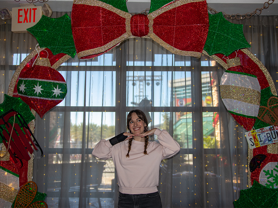 Woman posing underneath an arched bow photo op at Green & Red Coconut Club.