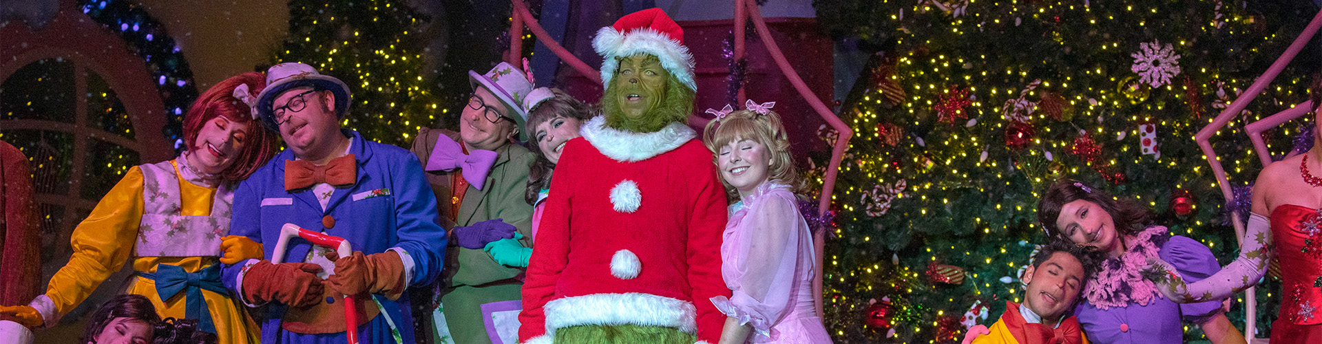 The Grinch, Cindy-Lou Who, and the Whos stand on stage as part of the Grinchmas Who-liday Spectacular