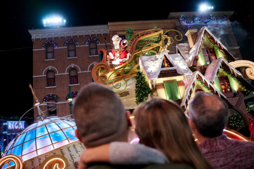 Santa waves at guests from a Macy's Universal Holiday Parade float