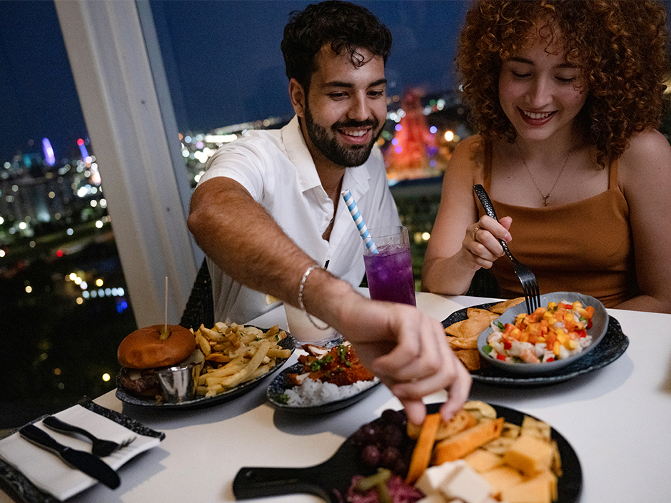 A man and a woman are enjoying snacks at a rooftop bar at Universal