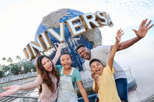 A family smiling and posing in front of the Universal Orlando Resort globe