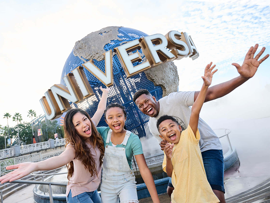 A family smiling and posing in front of the Universal Orlando Resort globe