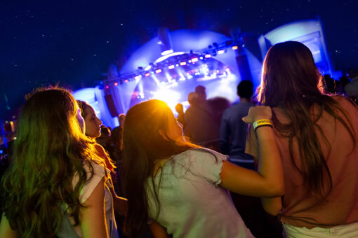Three girls arm-in-arm at a Universal Mardi Gras concert in Universal Studios Florida