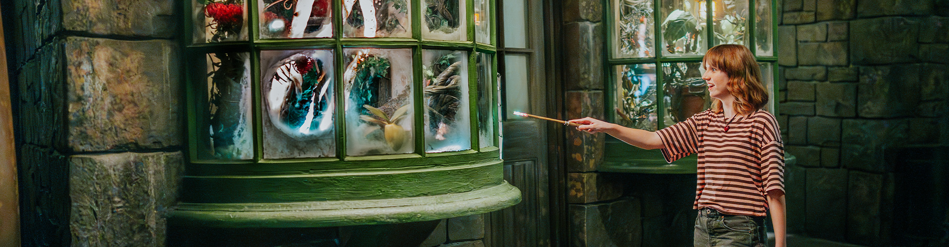 A young girl casts a spell with a 2nd Generation Interactive Wand in The Wizarding World of Harry Potter - Hogsmeade