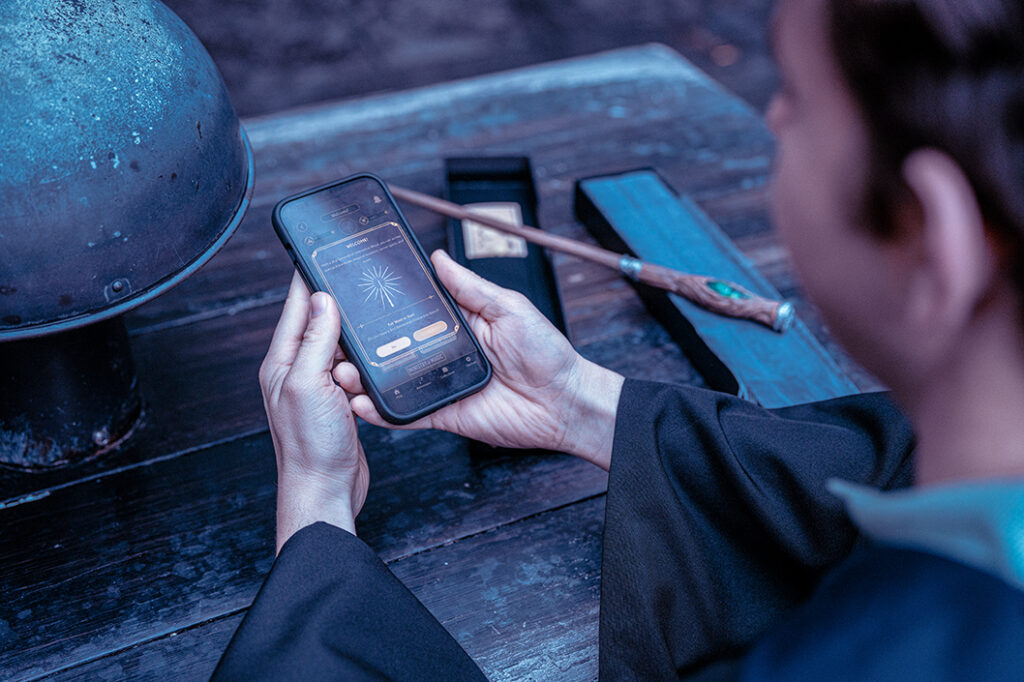 A young man pairs his 2nd Generation Interactive Wand with his phone using the Universal Orlando Mobile App