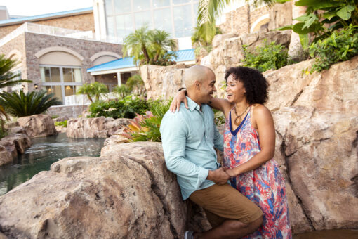 A couple poses together near a waterfall at Loews Sapphire Falls Resort