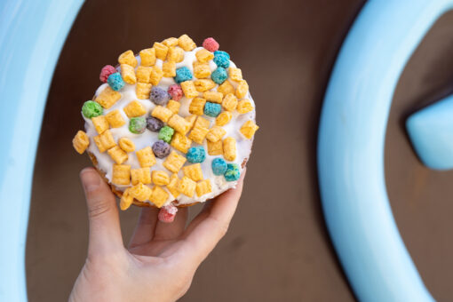 A guest holds up a colorful doughnut.
