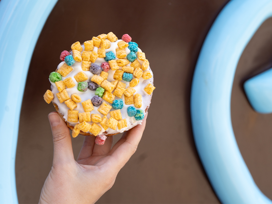A guest holds up a colorful doughnut.
