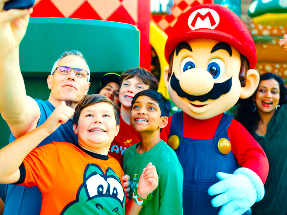 A family takes a selfie with Mario at SUPER NINTENDO WORLD.