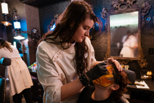 A makeup artist works on a guest in Darkmoor Monster Makeup Experience