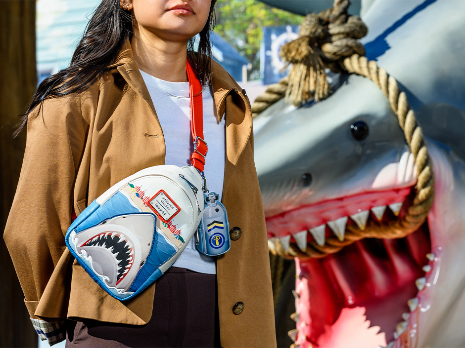A guest poses with a Jaws purse in front of the Jaws shark in Universal Studios Florida