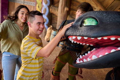 A young guest pets Toothless on the nose at Universal Epic Universe in the Isle of Berk