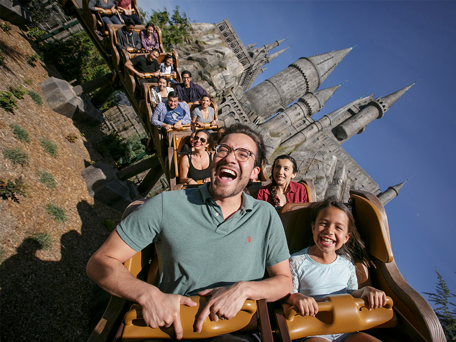 Guests on Flight of the Hippogriff, with Hogwarts Castle in the background.