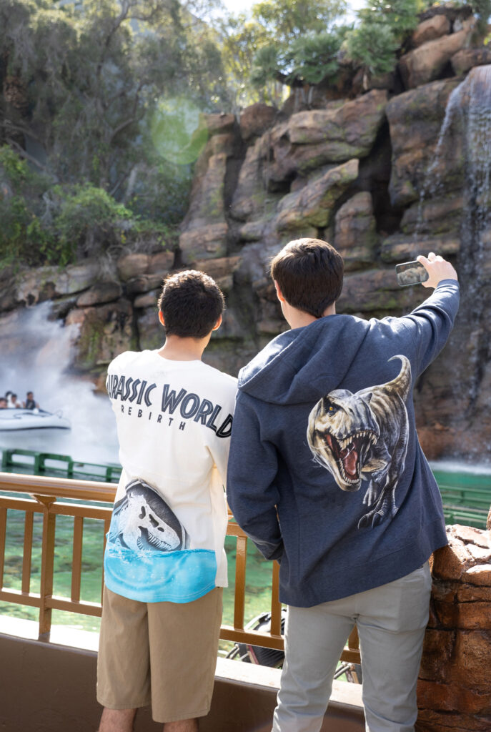 Guests sporting new Jurassic World Rebirth merchandise in front of Jurassic World - The Ride at Universal Studios Hollywood