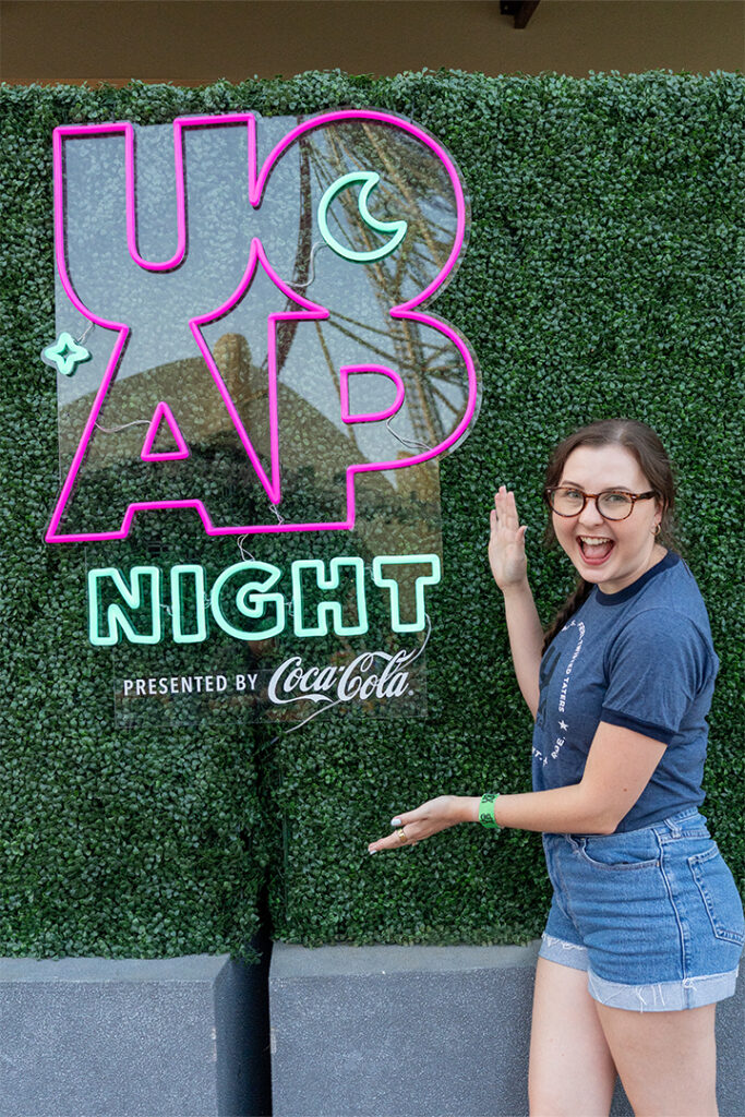 A guest posing with the UOAP Night neon sign