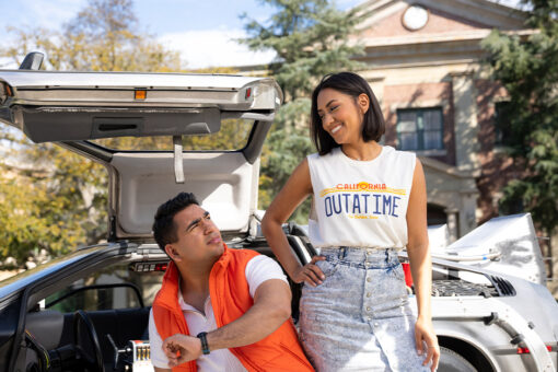 Two guests in Back to the Future merchandise pose with a time machine on the Universal Studios Hollywood Backlot