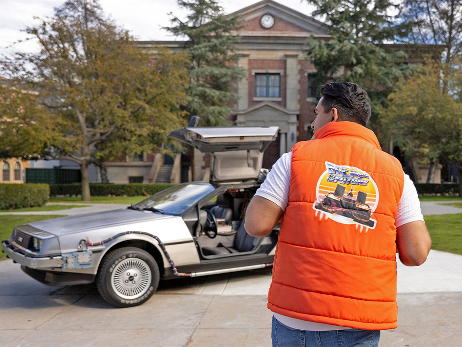 A guest in a Back to the Future puffer vest poses with the time machine