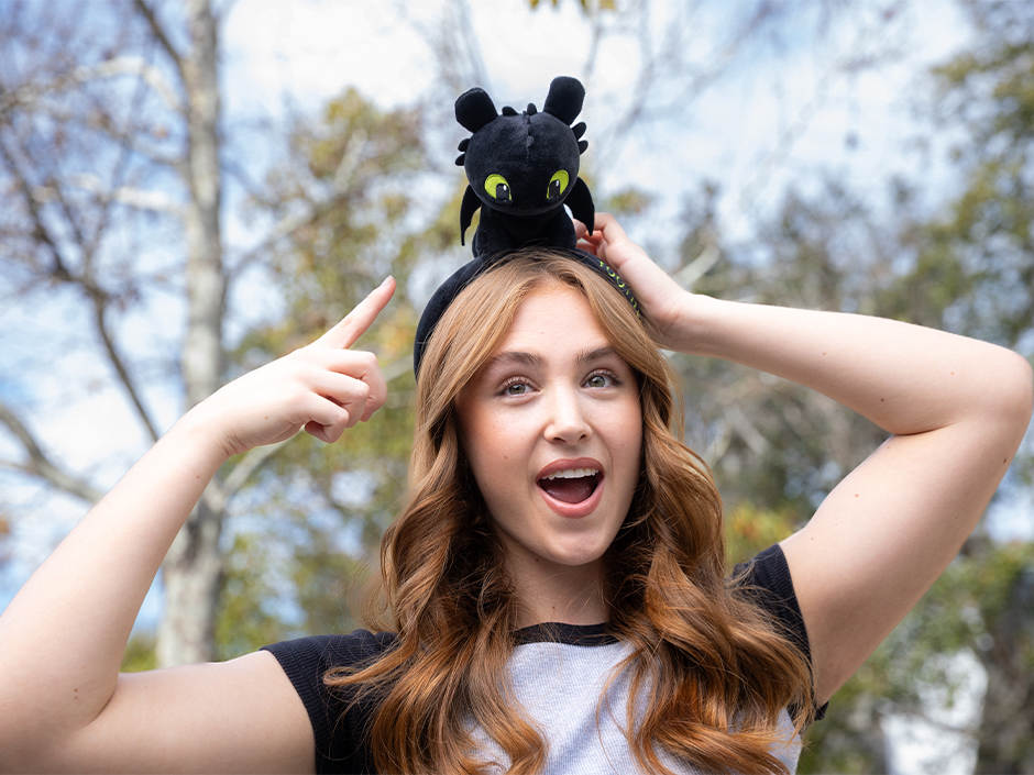 A guest smiles and points at her Toothless Headband