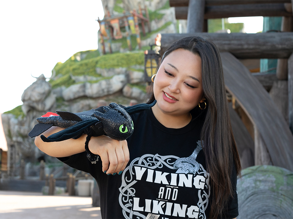 A guest holds the Toothless Hug and Glide plush