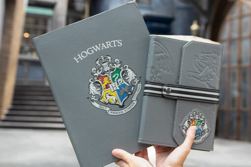Hands holding two gray Back to Hogwarts crest themed notebooks at Universal Orlando Resort.