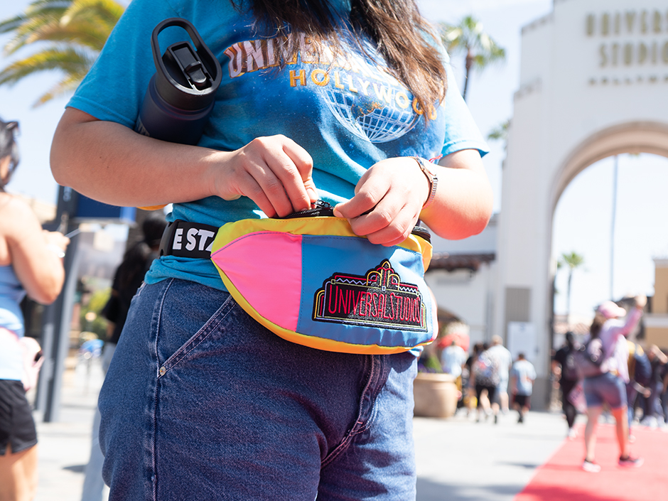 Person zipping up retro fanny pack in front of USH entrance