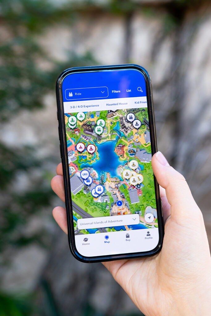 A hand holding up a phone that shows the Map screen of the Universal Orlando Resort App