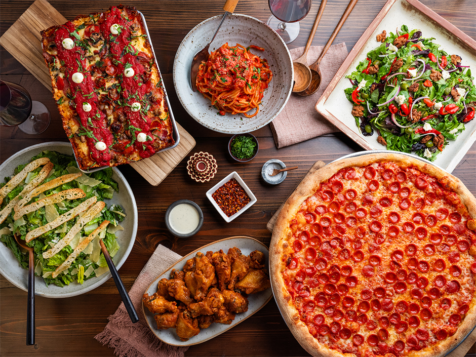 A table with pizzas, salads, wings and pasta on it at Slice House on CityWalk.