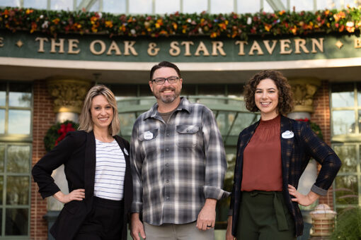 From left to right, Stephanie Trilli, Curtis Hopkins, Lindsey Ellis, standing in front of a holiday-decorated Oak & Star Tavern