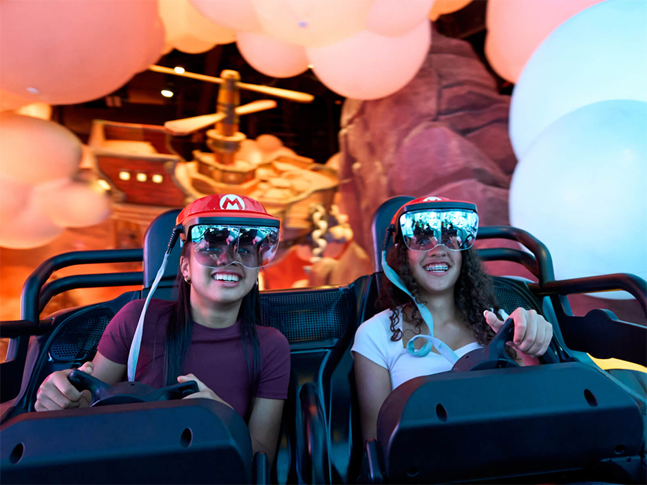 Two girls smile and ride Mario Kart: Bowser's Challenge in SUPER NINTENDO WORLD at Epic Universe