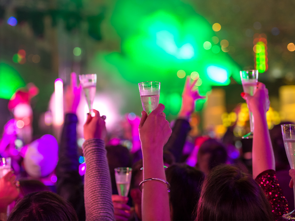 A crowd of hands holding up champagne glasses at Universal CityWalk for its New Year's Eve celebration.