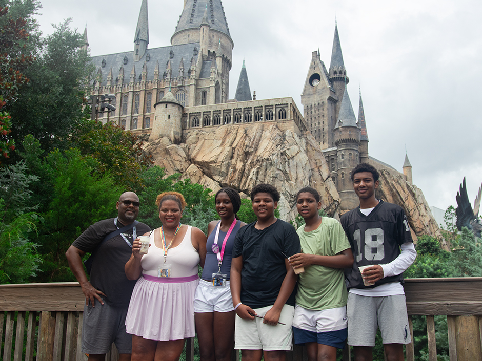 Maria Smith with her husband and children posing for a photo in front of the Hogwarts Castle in The Wizarding World of Harry Potter - Hogsmeade in Universal Islands of Adventure.