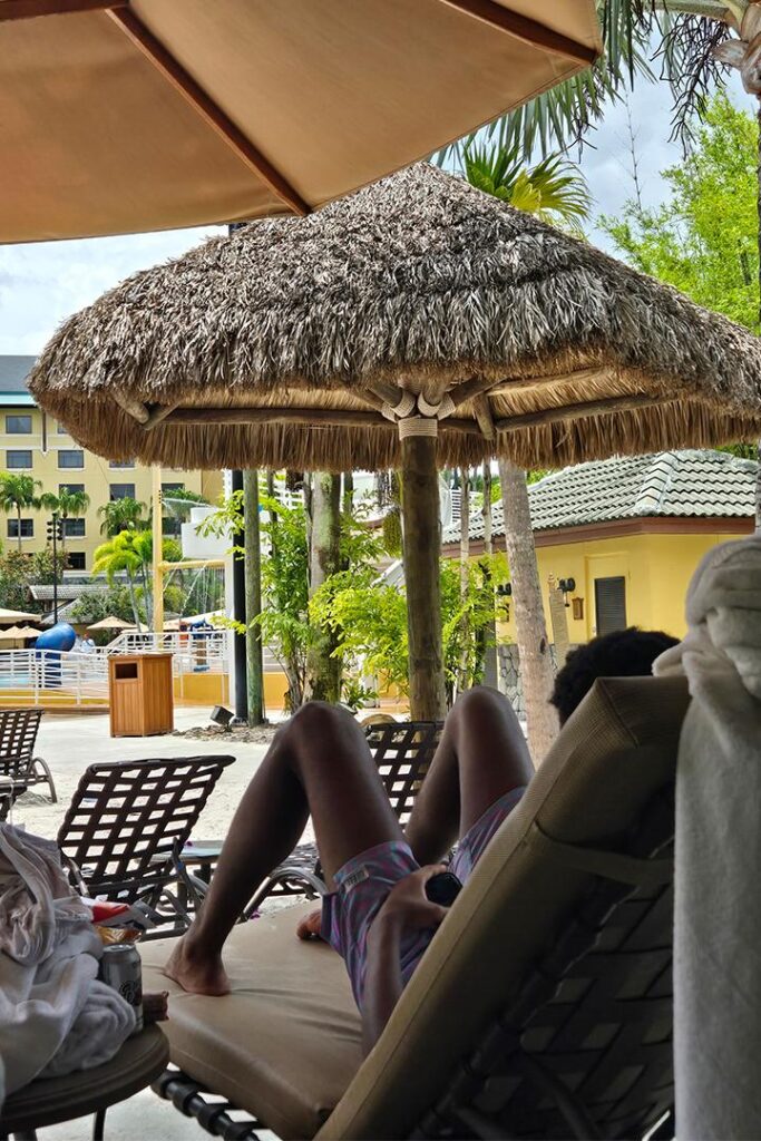 Maria's son lounging on a chair in front of the swimming pool at Loews Royal Pacific Resort.