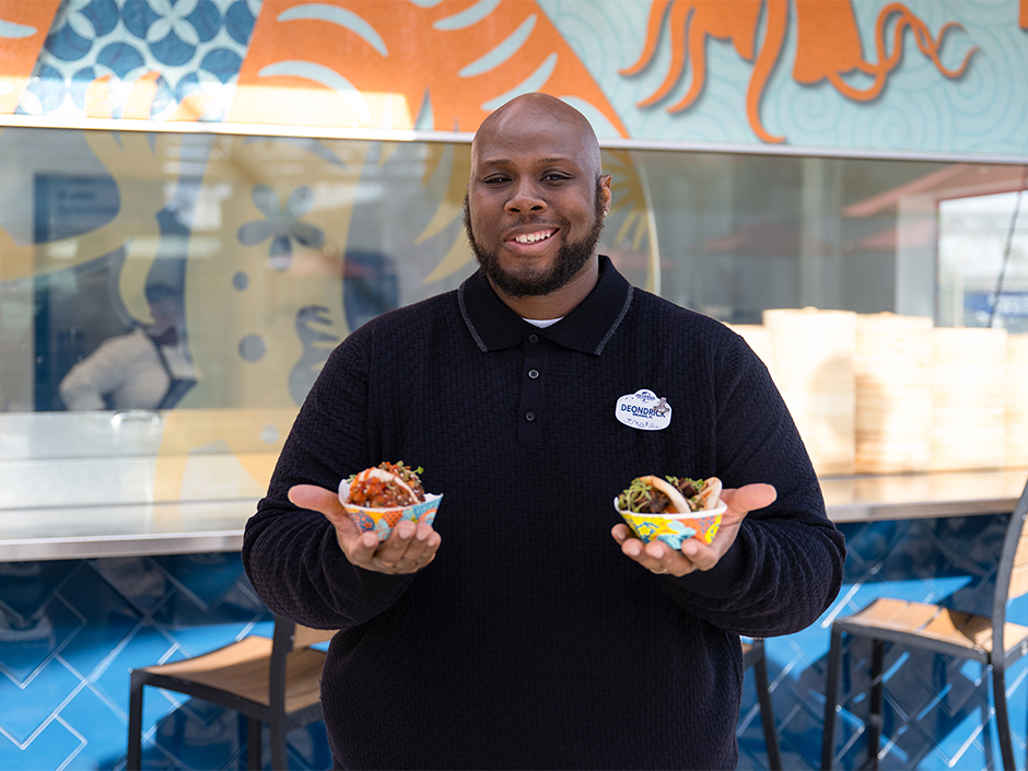 Chef Deondrick Williams holding two plates of bao at Bend the Bao.