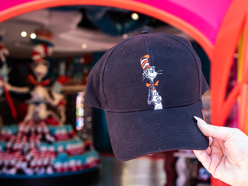 A guest holds up a black baseball cap with the Cat in the Hat on the front