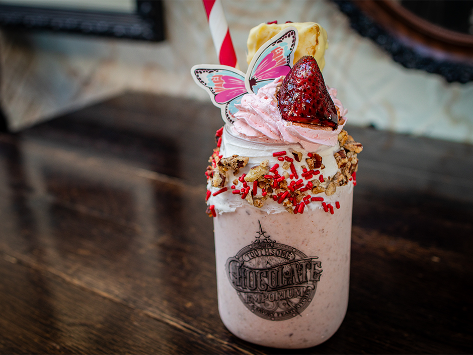 Jacques' Strawberry Love Potion Shake topped with strawberry whipped cream, a white chocolate butterfly, white chocolate strawberry cheesecake, and chocolate balsamic dipped strawberries at Toothsome in Universal CityWalk.