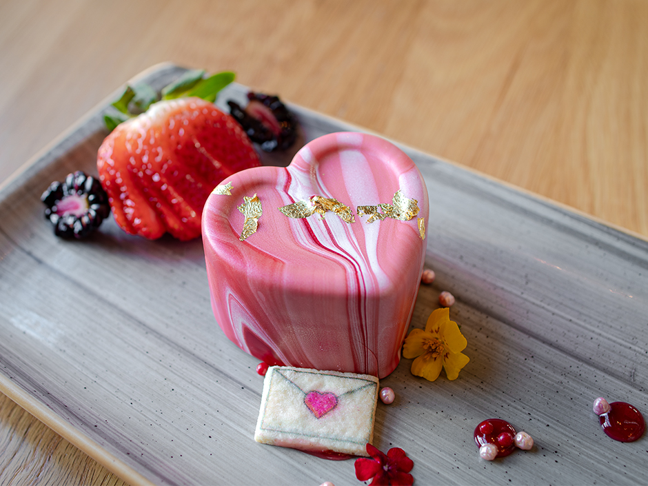 Heart-shaped Lychee Raspberry Cake with a side of sliced strawberries and blackberries at Bigfire for Valentine's Day.