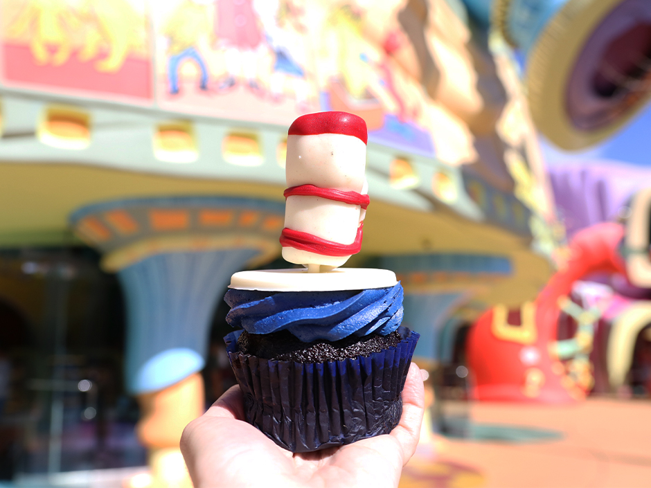 A hand holds up a The Cat in the Hat cupcake in Seuss Landing at Universal