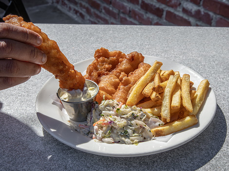 Hand dipping fried fish into tartar sauce at Pat O'Brien's in Universal CityWalk.
