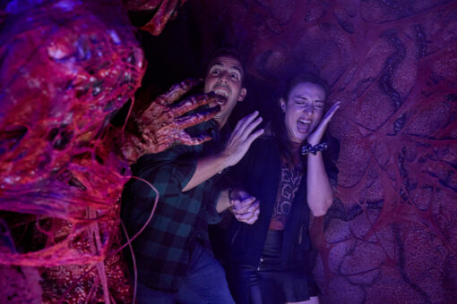 Two guests laugh and scream while being jump scared at Halloween Horror Nights