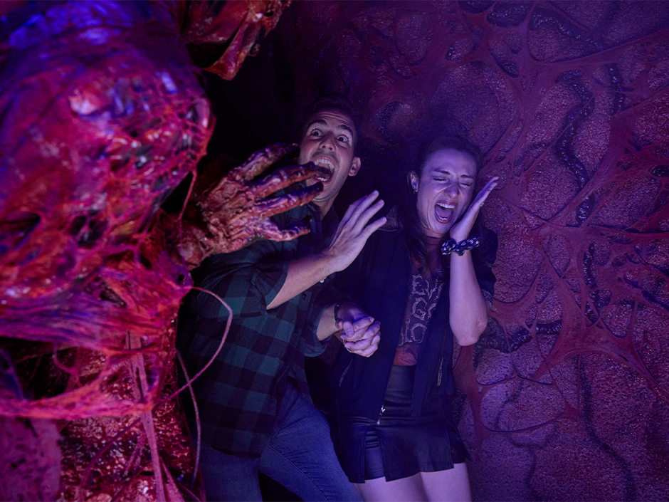Two guests laugh and scream while being jump scared at Halloween Horror Nights