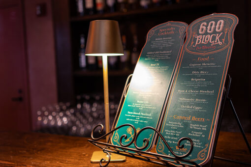 600 Block menus sitting on a bar top dimly lit by a table lamp.