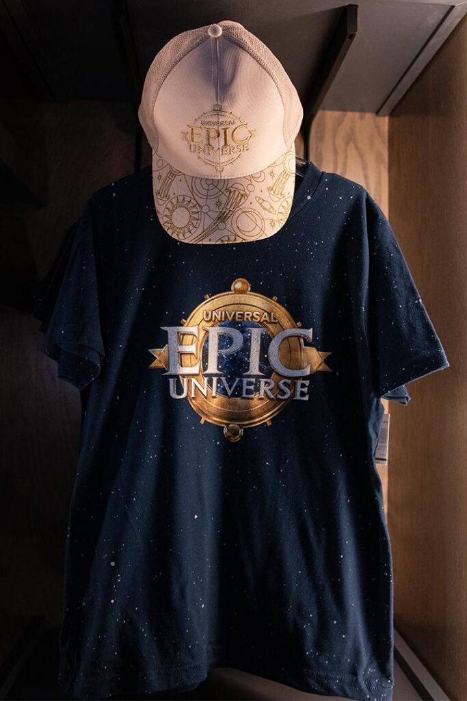 A blue Universal Epic Universe shirt and white and gold hat.