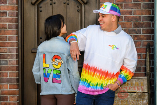Two friends pose side by side in Love is Universal merchandise form Universal Orlando